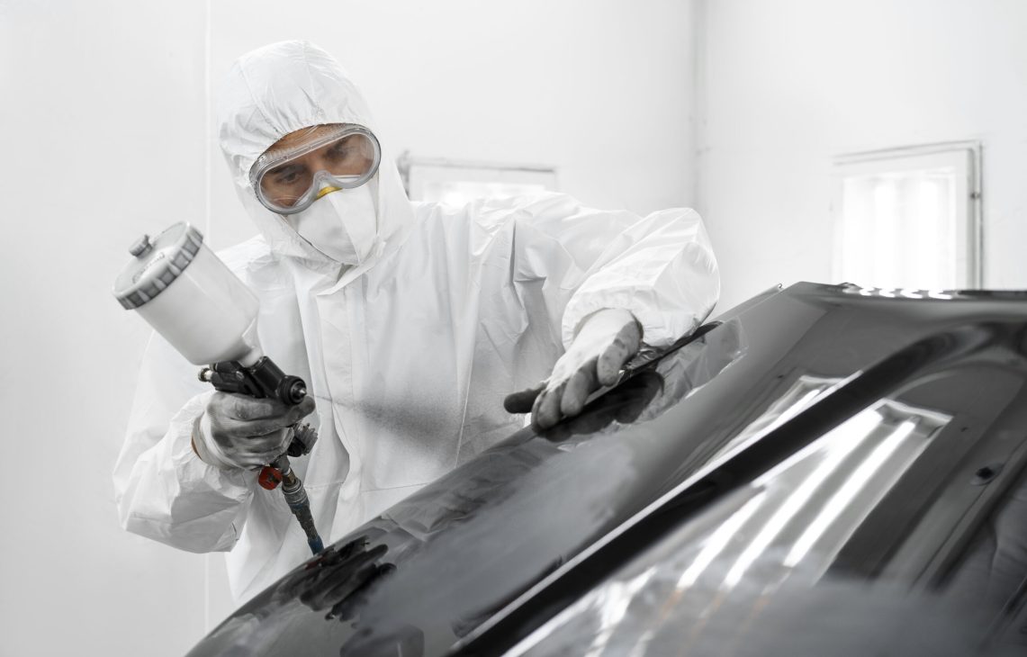 man-hazmat-suit-using-gun-paint-car-shop